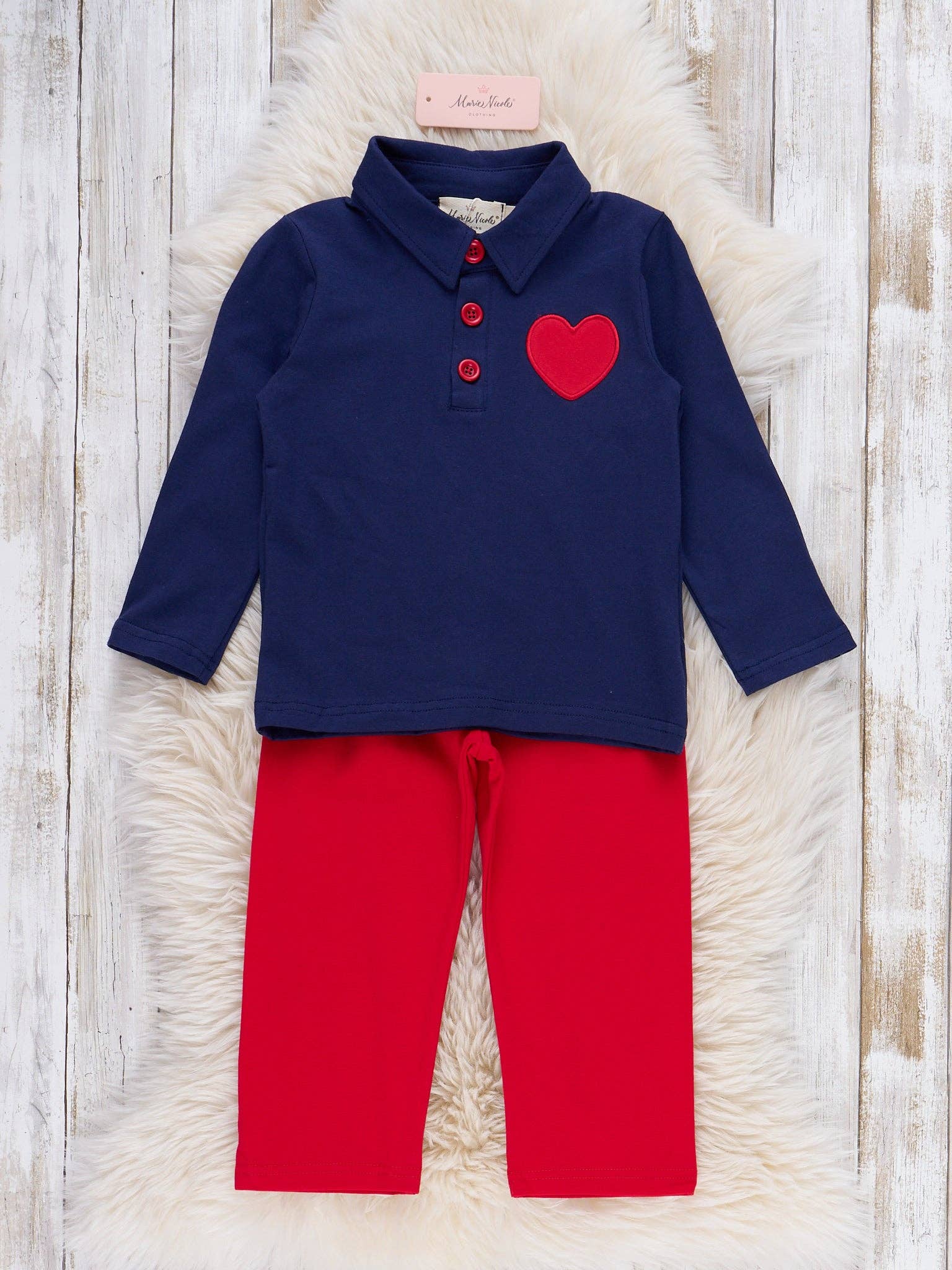 Navy blue shirt with red heart and red pants on a textured surface